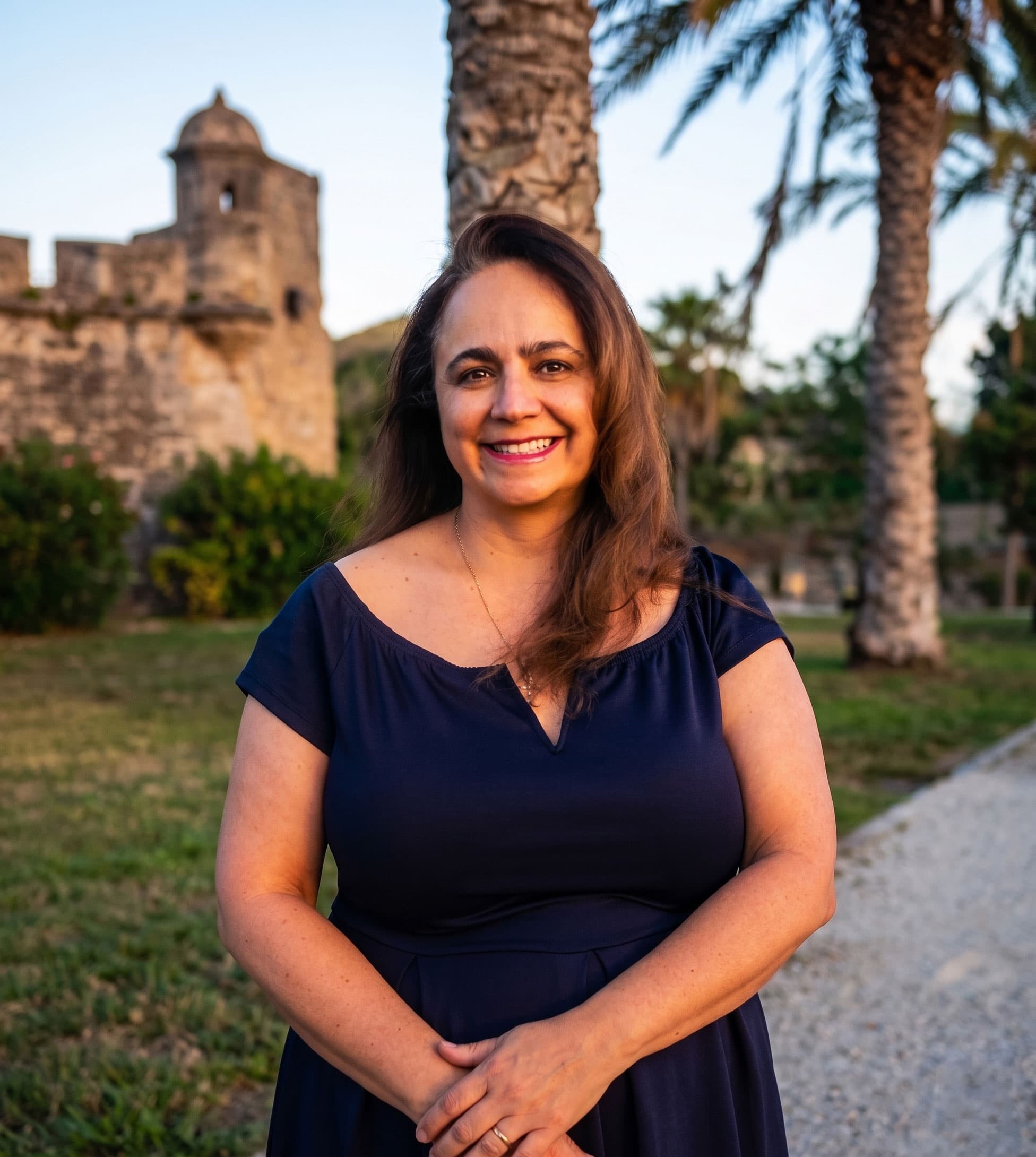 Gloria Marin standing outdoors near a historic mission tower